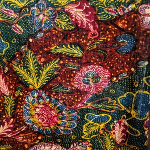 May include: A close-up of a colorful fabric with a floral pattern. The fabric is red, green, blue, and yellow. The flowers are intricate and detailed.