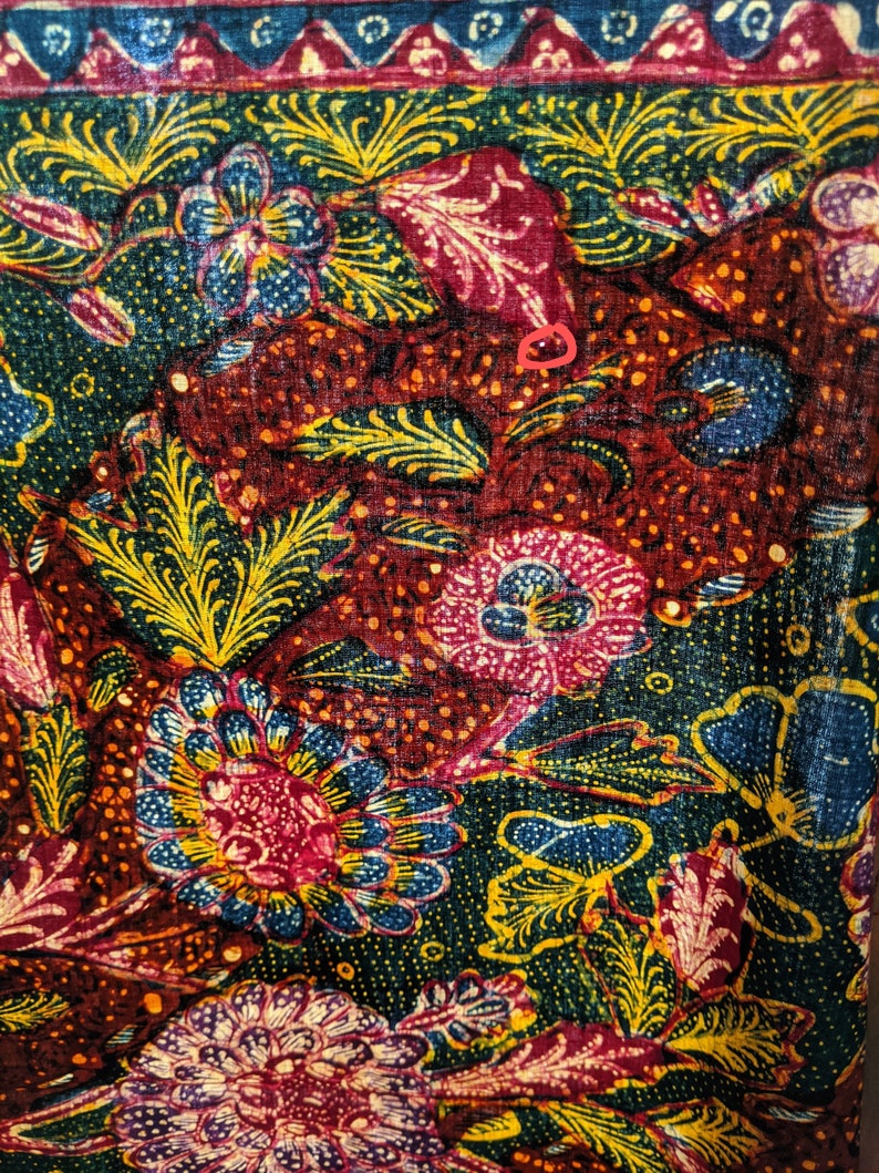 May include: A close-up of a colorful fabric with a floral pattern. The fabric is red, green, blue, and yellow. The flowers are intricate and detailed.