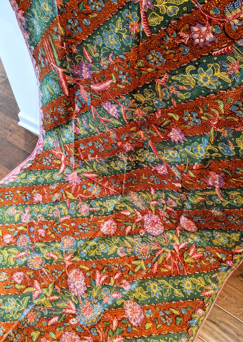May include: A colorful fabric with a repeating pattern of flowers and leaves. The fabric is a mix of orange, green, pink, and yellow.