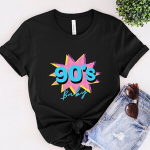 May include: Black t-shirt with a pink and yellow starburst graphic featuring the text "90's Baby" in blue.