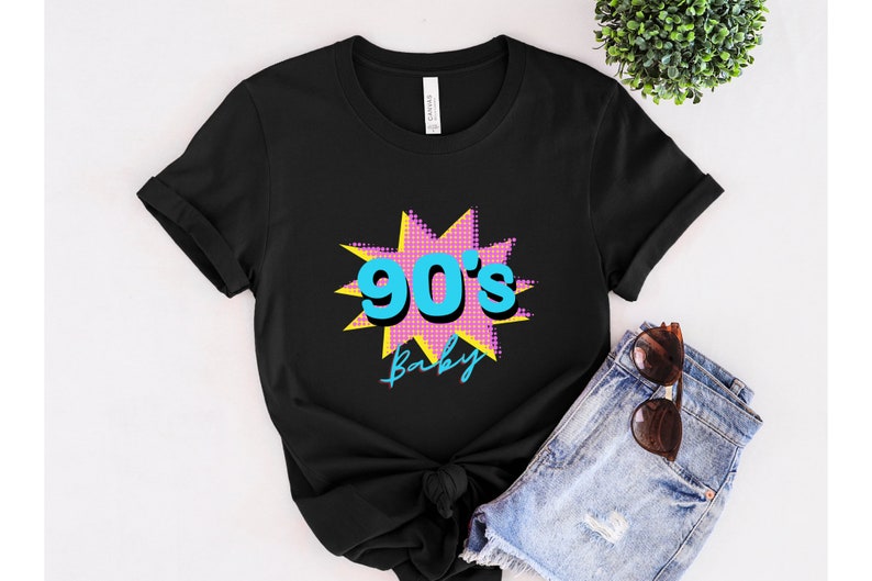 May include: Black t-shirt with a pink and yellow starburst graphic featuring the text "90's Baby" in blue.