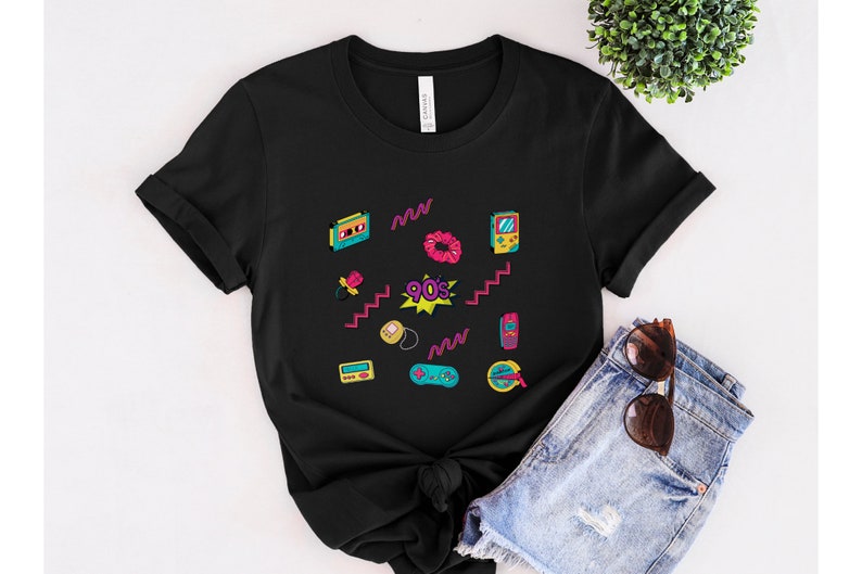 May include: Black t-shirt with a 90s theme featuring a variety of colorful retro icons, including a cassette tape, a scrunchie, a game console, and a cell phone. The text "90's" is printed in a pink and yellow starburst.