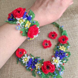 May include: A beaded flower necklace and bracelet set with red, blue, green, and yellow flowers. The set also includes a pair of matching earrings.