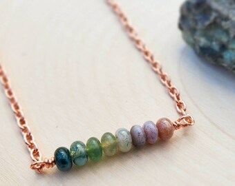 May include: A copper chain necklace with a row of seven green, brown, and pink agate beads.