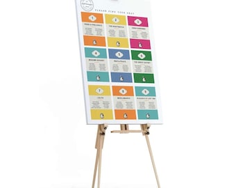 May include: A white seating chart with a penguin theme. The chart is on an easel and has nine squares with different colored backgrounds. Each square has a number and a book title. The chart says "Please find your seat".