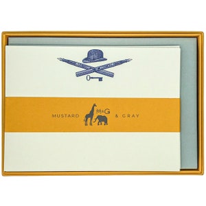 May include: A box of Mustard & Gray stationery featuring a blue illustration of a top hat, crossed pens, and a key. The box is yellow with the company name and "Mustard & Gray" printed in blue.
