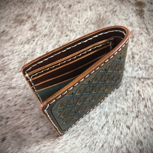 May include: A brown leather wallet with a blue and gold patterned design. The wallet has multiple card slots and a billfold.