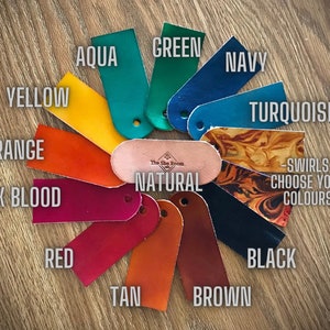 Puede incluir: Muestras de cuero en varios colores, incluyendo aguamarina, verde, azul marino, turquesa, amarillo, naranja, sangre de buey, rojo, marr&oacute;n claro, marr&oacute;n y negro. Las muestras est&aacute;n dispuestas en un c&iacute;rculo con la palabra "NATURAL" en el centro. El texto "SWIRLS - CHOOSE YOUR COLORS" tambi&eacute;n es visible.