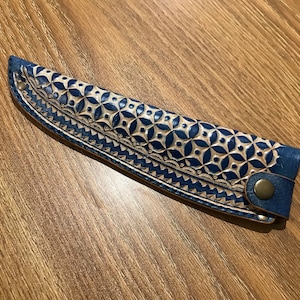 May include: A blue leather knife sheath with a white geometric pattern and a brass button.
