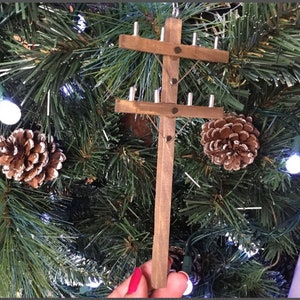 May include: A wooden miniature utility pole ornament with a brown finish and silver metal accents. The ornament is hanging on a green Christmas tree.