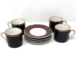 Puede incluir: Juego de cuatro tazas de espresso negras y doradas con platillos con estampado rojo y dorado.