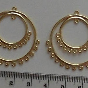 May include: Two gold-toned double hoop earrings with a decorative beaded edge. The earrings are approximately 5 cm in diameter.