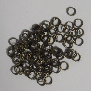May include: A pile of small, gold-toned metal jump rings. The rings are about 1.2 cm in diameter and are ideal for jewellery making.