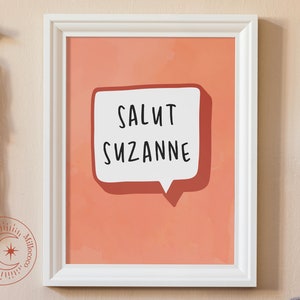 Może przedstawiać: Wydruk w ramie z brzoskwiniowym tłem i białą chmurką z napisem "Salut Suzanne".