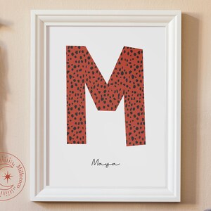 Peut inclure: Une impression encadrée blanche avec une lettre M rouge et noire avec un motif léopard. Le nom Maya est écrit en cursive noire sous la lettre.