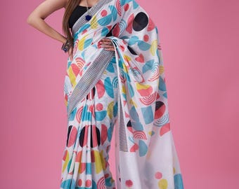 May include: A white saree with a geometric pattern in black, red, blue, and yellow. The saree has a black and white striped border.