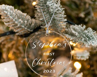 Könnte beinhalten: Runder, transparenter Weihnachtsbaumschmuck mit dem Text "Sophia's First Christmas 2023" in weißer Schrift.