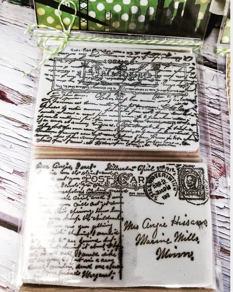 May include: Two vintage-style rubber stamps with black ink. The top stamp features a handwritten design with the text "Tous les pays derangery yeoptant pag la" and "Han forthen". The bottom stamp features a handwritten design with the text "Dear Angies Jones Millus fiel 2912" and "blindadAPTERIM". The stamp also features a vintage-style postage stamp with the text "POST CARD" and "FOR CORRESPONDENCE FOR ADDRESS".