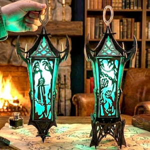May include: Two ornate black lanterns with detailed cut-out patterns, glowing teal. Each lantern has a handle and sits on a decorative base. The background shows a fireplace, bookshelves, and a map.