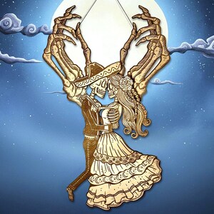 May include: A laser-cut wooden wall hanging featuring two skeletons dancing in traditional attire, including a sombrero and a ruffled dress. The figures are framed by two large, skeletal hands reaching upward toward a circular, pale moon background.
