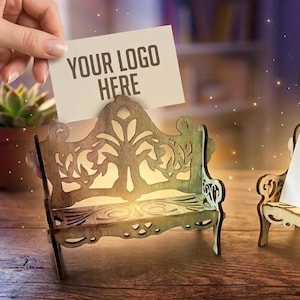 Könnte beinhalten: Zwei Visitenkartenhalter aus Holz in Form von Bänken. Einer ist dunkelbraun, der andere hellbraun. Jeder hält einen Stapel weißer Karten mit dem Text "YOUR LOGO HERE". Die Bänke haben aufwendige Ausschnitte.