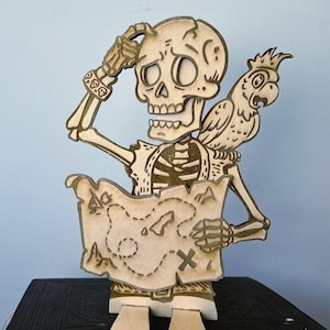 Puede incluir: Figura de esqueleto pirata de madera con un loro en el hombro, sosteniendo un mapa. El esqueleto se toca la cabeza en una pose pensativa. El mapa tiene una X que marca un lugar.