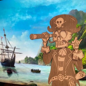 May include: A laser-cut wooden wall art piece depicting a skeleton pirate wearing a tricorn hat with a skull and crossbones. The figure holds a telescope to one eye, wears a coat with a cravat, and displays a hand gesture with a skull emblem.