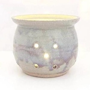 May include: A white ceramic pot with a light purple glaze and holes in the sides. The pot is round and has a slightly flared rim.