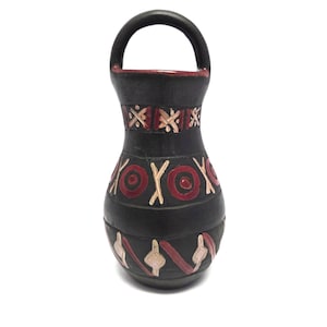 May include: A black ceramic vase with a handle, adorned with red, white, and beige geometric patterns. The vase has a rounded body and a cylindrical neck, showcasing a handcrafted aesthetic. The handle is a semi-circular shape.