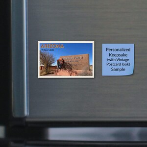 May include: A rectangular magnet featuring a scenic photograph of the Petrified Forest National Park entrance sign in Arizona. The text reads Arizona, October 2025, and Petrified Forest National Park. Next to it is a blue square note with text.