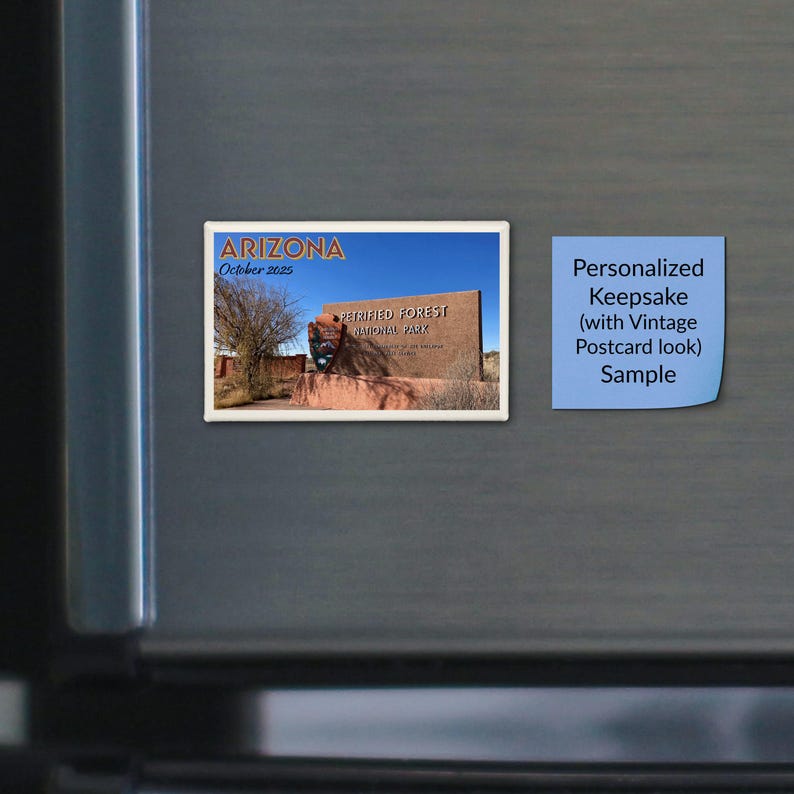May include: A rectangular magnet featuring a scenic photograph of the Petrified Forest National Park entrance sign in Arizona. The text reads Arizona, October 2025, and Petrified Forest National Park. Next to it is a blue square note with text.