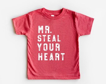 May include: Red short-sleeved t-shirt with the text "MR. STEAL YOUR HEART" printed in white.