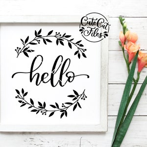 Puede incluir: Un cartel enmarcado blanco con una corona floral negra y la palabra "hello" en letra cursiva.