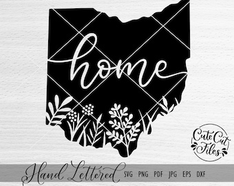 May include: Black and white silhouette of the state of Ohio with the word "home" written in a cursive font. The silhouette is surrounded by a border of stylized floral designs.