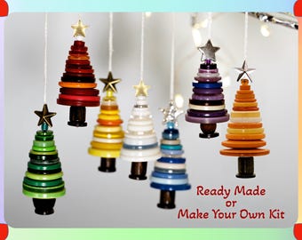 May include: Seven hanging ornaments shaped like Christmas trees, constructed from stacked colorful buttons with a star topper on each. The text "Ready Made or Make Your Own Kit" is printed in red in the lower right corner of the image.