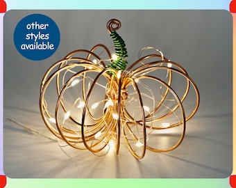 May include: A gold wire pumpkin with a green wire stem and white LED lights. The text "other styles available" is in a blue circle.