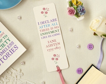 May include: A white bookmark with pink floral accents and the quote "I declare after all there is no enjoyment like reading" by Jane Austen. The bookmark has a pink ribbon attached.