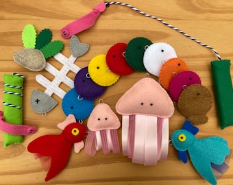 May include: A collection of felt craft ornaments including a white fish skeleton, a green bamboo-like tube, two jellyfish with ribbon tentacles, two bird-like figures, and a string of multi-colored felt circles in red, green, white, orange, and purple.