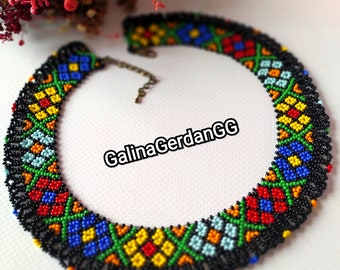 May include: A colorful beaded necklace with a black background and geometric patterns. The necklace is made of small, colorful beads and has a clasp closure. The necklace is called "GalinaGerdanGG".