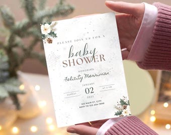 May include: A rectangular baby shower invitation card featuring a white background with light grey snowflake patterns, pine cones, and holly leaves. The text reads: Please join us for a baby shower honouring Felicity Merriman, January 02, 2025.