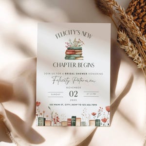 May include: A white rectangular bridal shower invitation card featuring a stack of watercolor books topped with flowers. Text reads: Felicity's New Chapter Begins, honoring Felicity Peterman, Sunday November 02 2025 at 2 PM, 123 Main St, City, RSVP 123-456-7890.