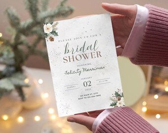 Puede incluir: Una tarjeta de invitación rectangular para una despedida de soltera con fondo blanco e ilustraciones invernales de piñas, hojas de acebo y copos de nieve. El texto dice: Please join us for a bridal shower, honoring Felicity Merriman.