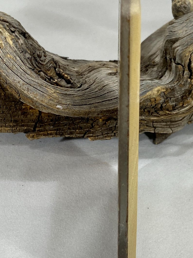 K&ouml;nnte beinhalten: Ein d&uuml;nnes, rechteckiges, helles Holzbrett mit einer glatten, flachen Oberfl&auml;che und einer dunklen, schmalen Kante, das vertikal vor einem St&uuml;ck verwittertem, strukturiertem Treibholz mit tiefen Rillen und brauner Oberfl&auml;che steht.