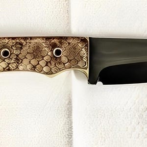 K&ouml;nnte beinhalten: Ein feststehendes Messer mit einer dunkel polierten Stahlklinge und einem Griff mit strukturiertem, hellbraunem und braunem Schlangenhautmuster. Der Griff ist mit drei kreisf&ouml;rmigen Metallnieten befestigt, die einen Kontrast zur Klinge bilden.
