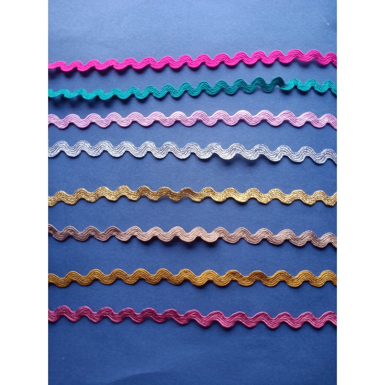 May include: Assortment of eight wavy trim ribbons in various colors, including pink, teal, light pink, silver, gold, peach, gold, and magenta.