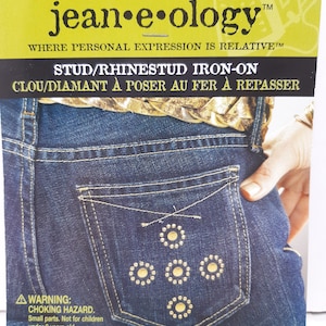 May include: A close-up of a blue jean pocket with five gold iron-on rhinestones in a circular pattern. The package reads "Stud/Rhinestud Iron-On" and "Clou/Diamant à poser au fer à repasser".