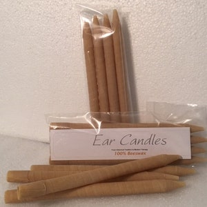 May include: A close-up of a package of ear candles. The package is labeled "Ear Candles 100% Beeswax". The candles are made of natural beeswax and are designed to be used in the ear to help relieve earwax buildup.