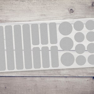 Könnte beinhalten: Eine Folie mit transparenten, weißen Schutzaufklebern für Fahrräder. Die Folie enthält verschiedene Formen und Größen, darunter Kreise und Rechtecke.