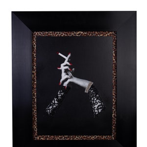 Pode incluir: Uma fotografia em preto e branco emoldurada de um par de mãos com esmalte de unha vermelho segurando um cigarro. As mãos estão usando luvas de renda preta e um anel de diamante. A moldura tem uma borda de estampa de leopardo.