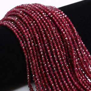 May include: A strand of deep red faceted gemstone beads. The beads are small and uniform in size, creating a smooth and elegant look.